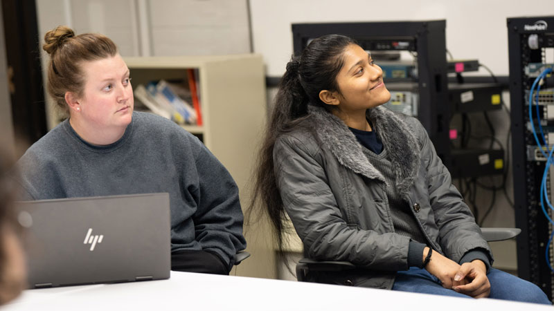 Two female students inside classroom on McNichols Campus