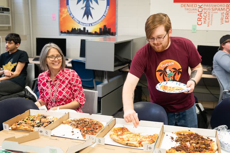 Students gathering around pizza at one of the cyberclub meetings