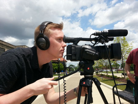 Male student filming on baseball field