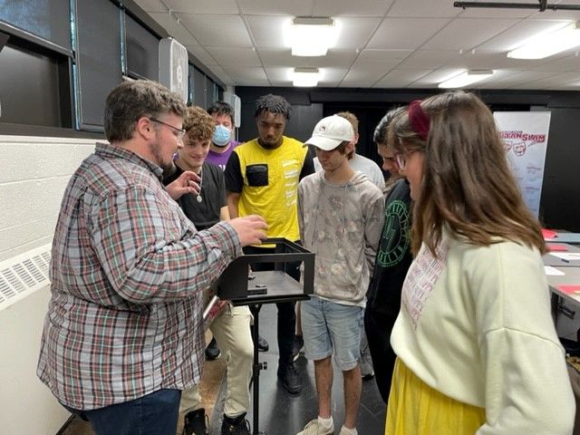 An instructor shows students a model set.