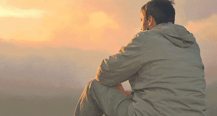 Image of man sitting on a mountain looking contemplative